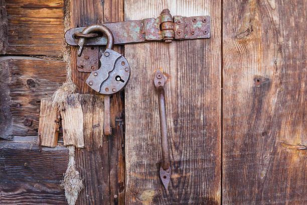 Old rusty padlock and latch on a wooden door with rusty nails