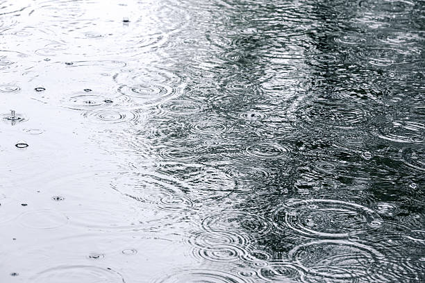istock raindrops and sky reflection on water surface of puddle 614503076