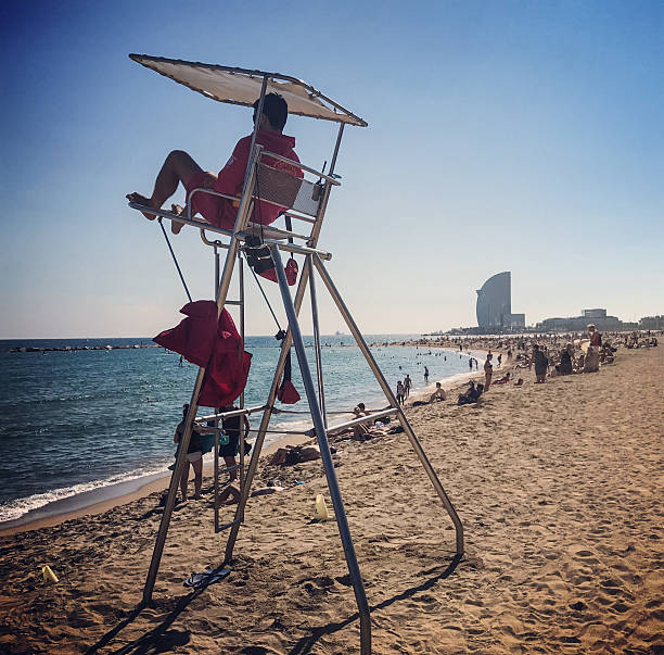 Barcelona, Spain - September 30, 2016: Lifeguard on Barcelonetta Beach, Barcelona, Spain. Tourists enjoying Barcelonetta beach with W hotel on background. 