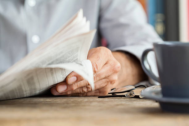 Man newspaper reading on table Man newspaper reading on table company news stock pictures, royalty-free photos & images