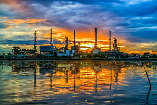 oil refinery at twilight and water reflection stock photo