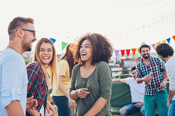 Rooftop celebration Group of young people chatting and laughing on a rooftop party. social interaction stock pictures, royalty-free photos & images