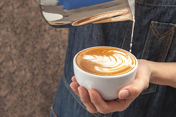 barista is pouring milk into a cup of cafe latte - latte macciato stok fotoğraflar ve resimler
