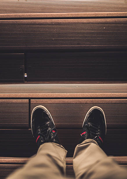 istock Man's feet on the stairs with lighting 614510846
