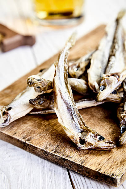 istock Dried fish on chopping board, mug of beer behind 614512728