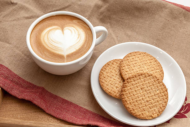 istock coffee with heart shaped latte art serve with some biscuits 614513220