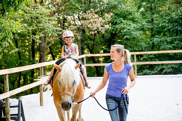 bambina che impara a cavalcare un cavallo - teaching child horseback riding horse foto e immagini stock