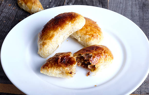 istock Small empanadas with meat on a white plate. 614515298
