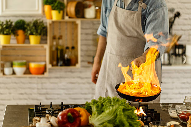 istock Male chef holding flaming pan over stove 614515802