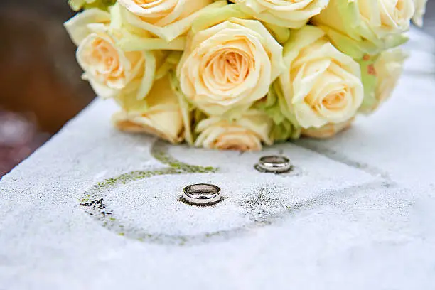 Photo of Wedding flowers and rings on frozen surface