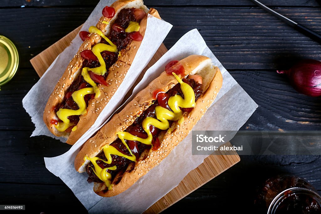 Homemade New York Style Hot Dog with Onion sauce Homemade New York Style Hot Dog with Onion sauce. Dark wood background with onion and tongs on back Hot Dog Stock Photo