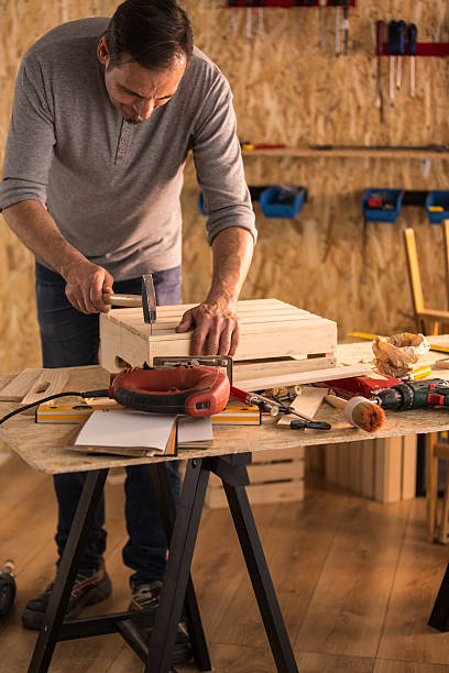 istock Carpenter hammers nail into a wooden crate 614517492