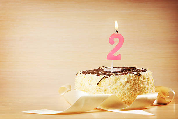 istock Birthday cake with burning candle as a number two 614518688