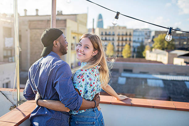 istock Young couple standing together on a rooftop party 614532180