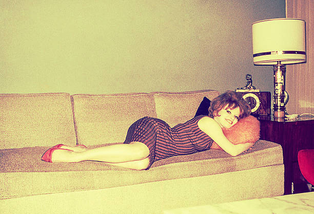 Vintage photo of a young woman of the sixties laying down on a sofa.