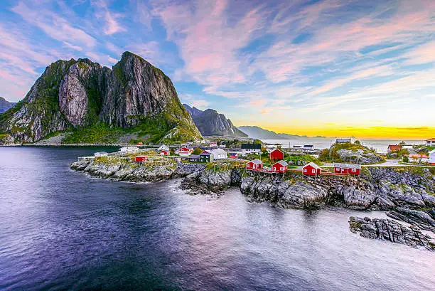 Popular view of Fishing hut (rorbuer) in Hamnoy, Norway with Lilandstinden mountain peak as the background during sunrise
