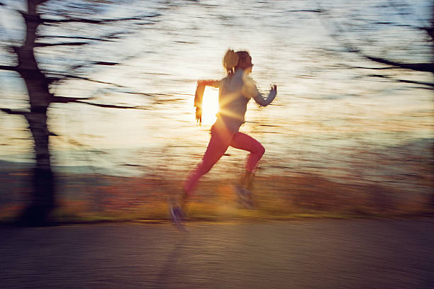 Photo of a female jogger in the park, with sun flare in the background.