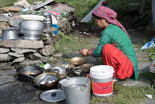 Woman cleaning utensils outdoor in Shimla, Himachal Pradesh, India.