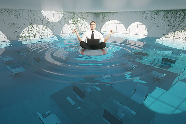 istock Businessman meditating in flooded office 614537096