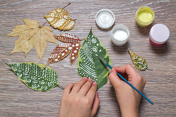 Girl paints patterns of dry autumn leaves stock photo