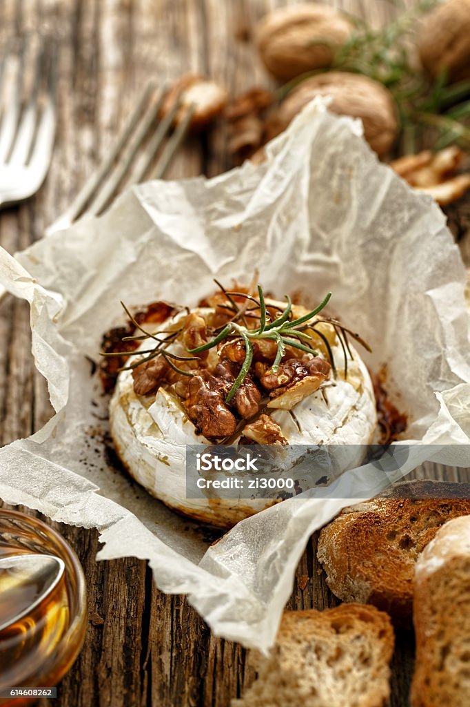 Baked Camembert with walnuts, honey  and rosemary on wooden table Baked Camembert with walnuts, honey  and rosemary on wooden rustic table Camembert Stock Photo