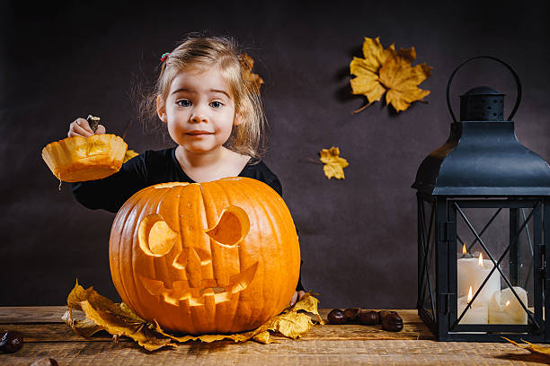 istock girl poses with a Halloween pumpkin 614608304