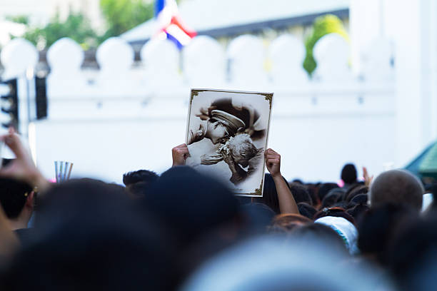 Griefing crowd in Bangkok Bangkok, Thailand - October 15, 2016: View over heads of griefing crowd of thai people at second day of condolence of King Bhumipol near Wat Phra Kaeo. Somebody is holding up photo of young king with a an old woman, thailand king stock pictures, royalty-free photos & images