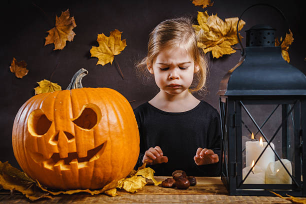 istock girl poses with a Halloween pumpkin 614608796