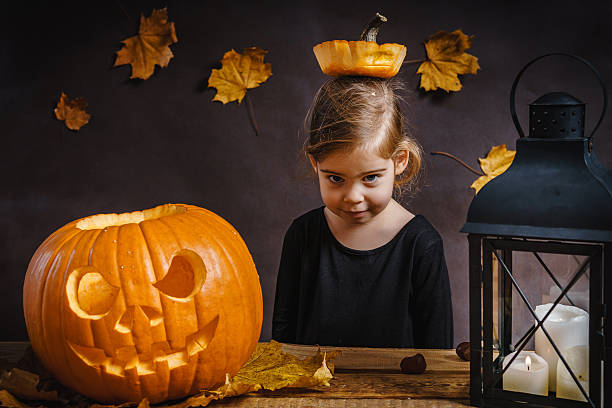 istock girl poses with a Halloween pumpkin 614610118