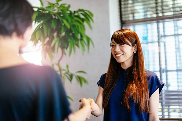 Two young Japanese businesswomen analyzing potential investments and handshake for successful cooperation. Image taken with Nikon D800 and developed from RAW in XXXL size. Location: Kyoto, Japan