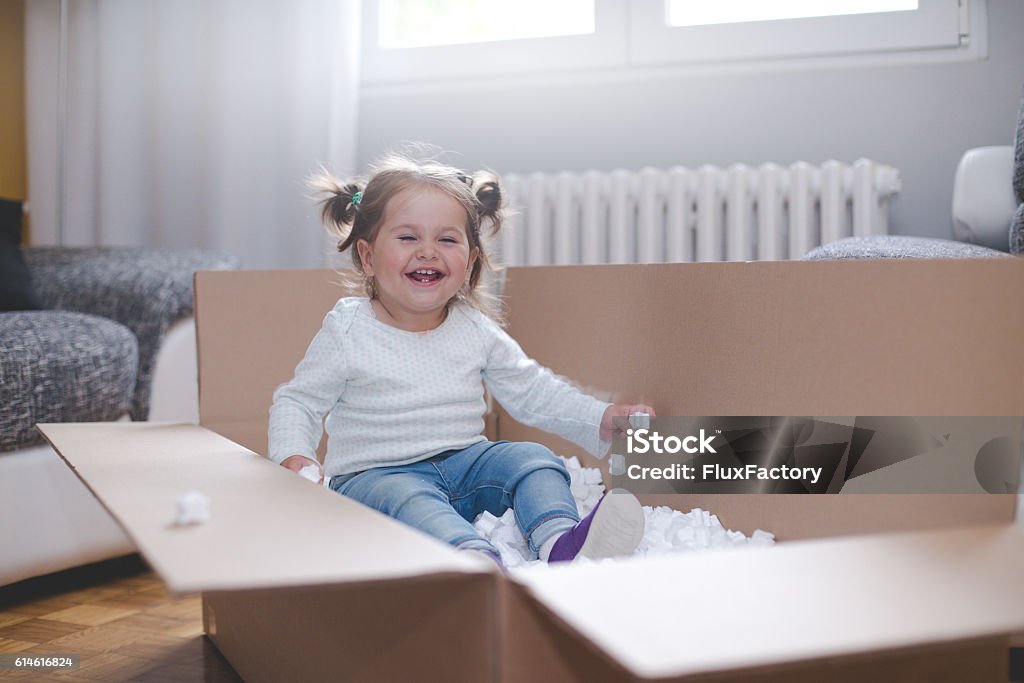 baby girl playing in box with styrofoam pellets Little girl in a box.  Baby - Human Age Stock Photo
