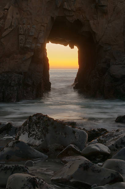 istock Sunset and ocean through natural rock tunnel. 614618488