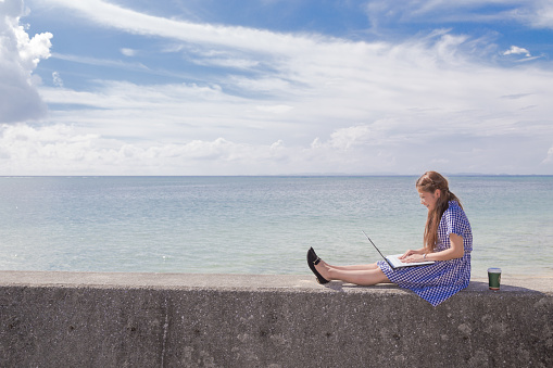 Young woman operating computer on the beach