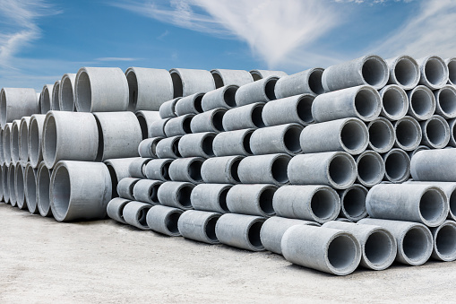 Stack of concrete drainage pipes for wells and water discharges with blue sky