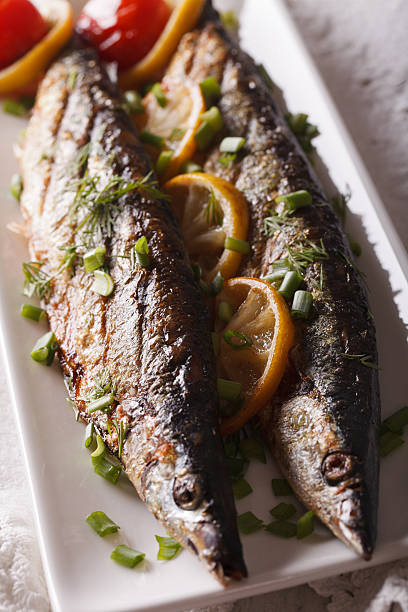 istock Tasty grilled saury with lemon on a plate close-up. vertical 614626124