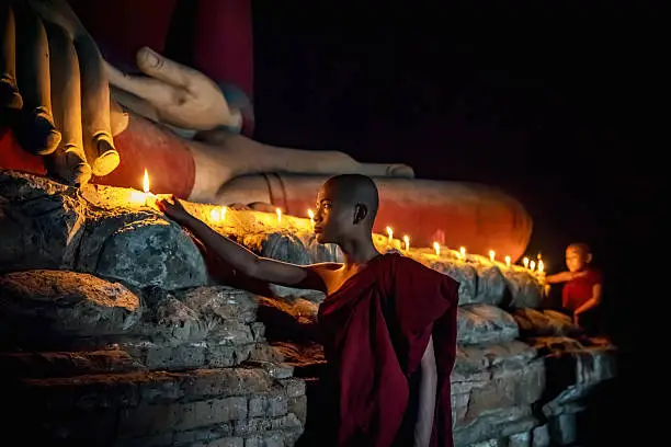 Photo of Novice Monks lighting Candles to worship Buddha Temple Bagan Myanmar