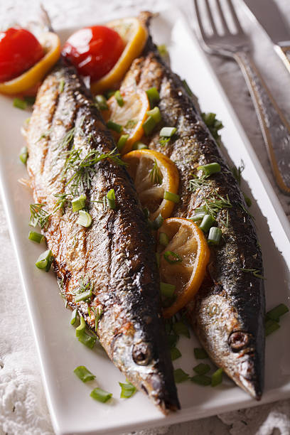 istock Fish saury grilled with lemon and chives on plate close-up 614626988