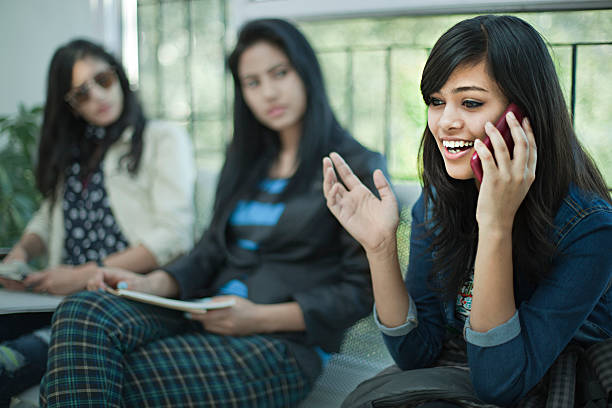 junge geschäftsfrau spricht laut am telefon im büro wartezimmer. - indian ethnicity audio stock-fotos und bilder