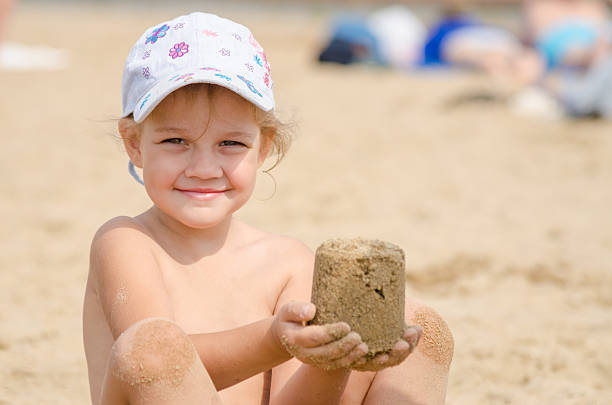 istock Girl keeps hands on turret of sand 614628344