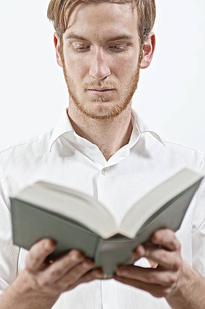 istock Standing Young Adult Man Keeps a Book in His Hands 614635764