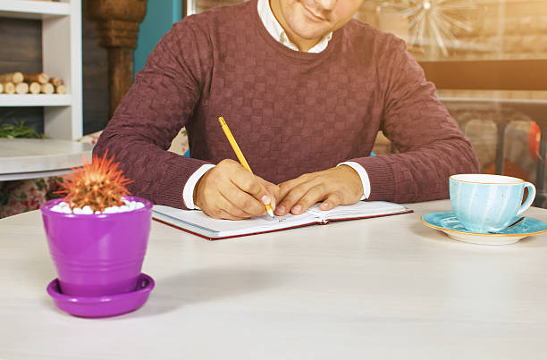 istock Man holding pencil and writing on a paper in the 614639032