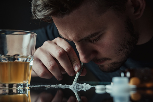 Man snorting cocaine in dark room. Drug addict concept.