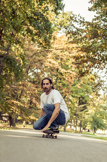 istock Skateboarder squatting on a skateboard and ride through the forest 614644640