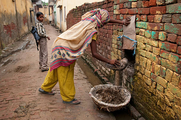 Manual Scavenger PANIPAT, HARYANA, INDIA - Aug 5 2010: A lowe caste lady practices the illegal process of manual-scavenging from a home; the removal of human waste by hand. caste system stock pictures, royalty-free photos & images