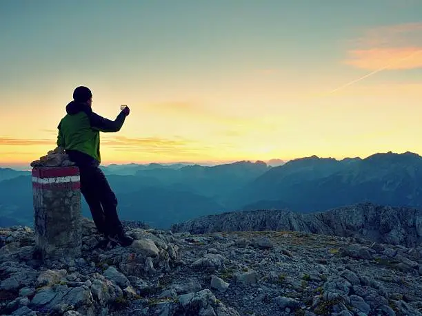 Photo of Hiker takes selfie photo. Morning in Alpine mountain.