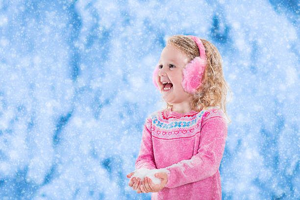 istock Little girl playing with snow flakes 614647844