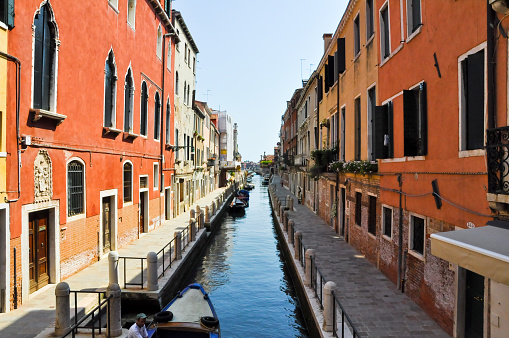 Venice, Italy - July 23, 2010: Narrow Venetian canal with boats parked on the left side of the canal in Venice, Italy.