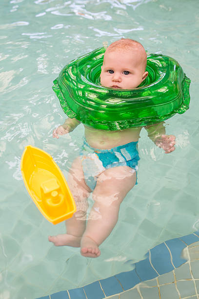istock Baby in inflatable ring floating in swimming pool. 614648886