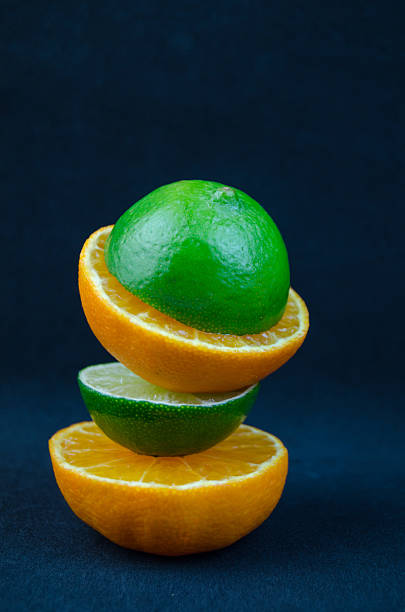 The fruit of lime and mandarin cut in half, on a dark background.