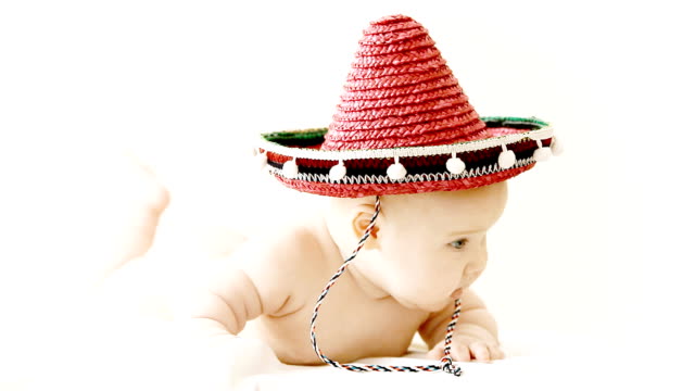 Baby in sombrero hat with maracas on the light background